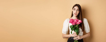 浪漫的情人节一天概念梦幻女人花束粉红色的玫瑰标志持有花米色背景