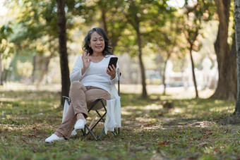 快乐高级亚洲女人户外公园会说话的视频调用家庭