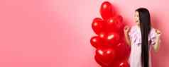 亚洲十几岁的女孩长头发欢呼情人节一天浪漫的礼物标志微笑快乐跳快乐情人礼物心气球粉红色的背景