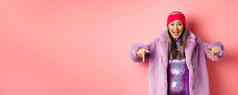 时尚购物概念快乐朝鲜文高级女人指出手指显示太棒了促销交易穿时尚的紫色的皮毛外套头巾粉红色的背景