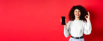 有吸引力的女人智能手机显示<strong>标志</strong>空电话斯雷恩<strong>推荐</strong>购物应用程序站红色的背景
