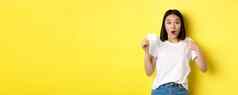年轻的亚洲女人休闲白色t恤显示塑料信贷卡微笑相机黄色的背景