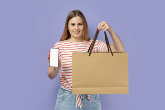 女人站持有购物袋显示聪明的电话空显示广告
