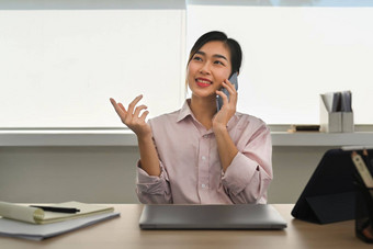 积极的亚洲女投资者电话谈话业务合作伙伴坐着工作场所