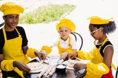 童年烹饪活动跨国公司孩子们黑色的非洲高加索人孩子们黄色的厨师他围裙统一的快乐公司多民族孩子们烹饪面团