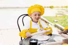 英俊的烹饪孩子黄色的厨师他围裙黄色的统一的持有面团辊烹饪面团户外