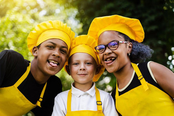<strong>跨国公司</strong>公司孩子们厨师黄色的制服微笑扮鬼脸显示舌头户外非洲少年黑色的女孩有趣的高加索人孩子男孩烹饪食物