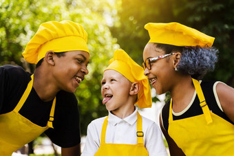 <strong>跨国公司</strong>公司孩子们厨师黄色的制服微笑扮鬼脸显示舌头户外非洲少年黑色的女孩有趣的高加索人孩子男孩烹饪食物
