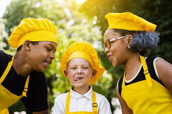 跨国<strong>公司公司</strong>孩子们厨师黄色的制服微笑扮鬼脸显示舌头户外非洲少年黑色的女孩有趣的高加索人孩子男孩烹饪食物