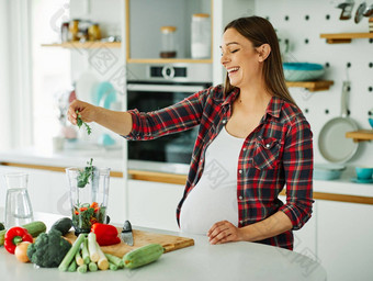 女人怀孕了食物健康的女蔬菜<strong>怀孕妈妈</strong>。准备吃首页年轻的沙拉快乐孕妇健康厨房饮食绿色举止优雅的人