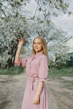 金发女郎女孩春天走花园樱桃花朵女肖像特写镜头女孩粉红色的波尔卡点衣服