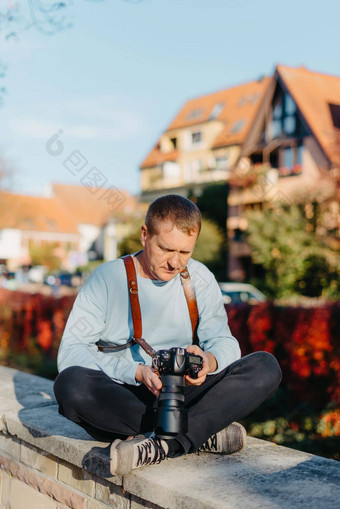 男人。坐着欧洲城市持有照片相机当代时尚的博主<strong>摄影</strong>师英俊的男人。采取<strong>自拍</strong>旅行欧洲