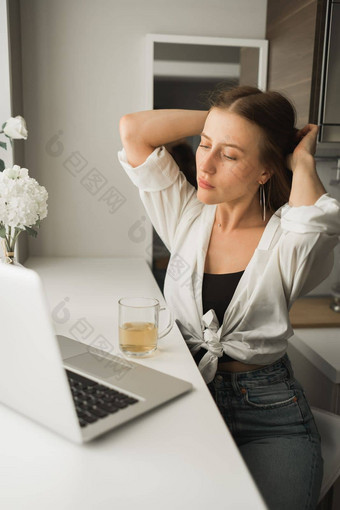 关闭年轻的漂亮的女人喝茶打破打字浏览在线移动PC工作电脑坐着舒适的房间距离学习工作打破咖啡时间概念