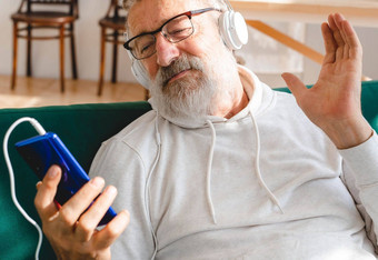 上了年纪的男人。很酷的有胡子的男人。移动电话视频调用幸福上了年纪的生活方式人概念视频调用智能手机房间挥舞着屏幕聊天孩子们现代技术沟通互联网
