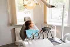 孩子镜子牙医快乐孩子病人牙科牙齿治疗有吸引力的孩子女孩坐着牙科办公室微笑