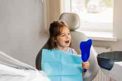 牙齿治疗孩子镜子牙医快乐孩子病人牙科有吸引力的孩子女孩坐着牙科办公室微笑