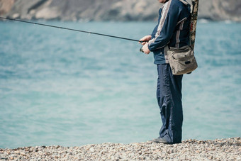 男人。爱好钓鱼海收紧钓鱼行卷鱼夏天平静表面海特写镜头渔夫手扭卷钓鱼行杆钓鱼海在户外慢运动