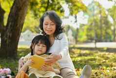 充满深情的祖母可爱的孩子阅读阅读阅读仙女演讲阳光明媚的夏天花园