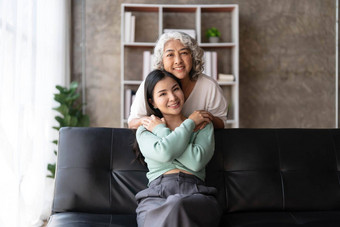 爱的成人女儿拥抱老妈妈。站沙发上首页家庭享受温柔的时刻年轻的女人成熟的妈<strong>妈祖</strong>母一代又一代