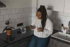 肖像非洲美国女学生穿着随便持有移动电话打字消息沟通朋友社会网络高互联网连接厨房复制空间
