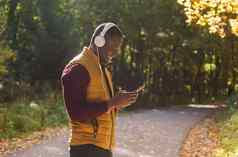 肖像非洲美国男人。听音乐秋天公园复制空间的地方广告小工具应用程序流媒体服务概念