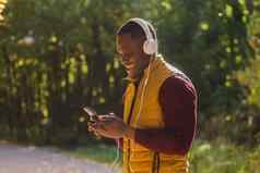 肖像非洲美国男人。听音乐秋天公园复制空间的地方文本小工具应用程序流媒体服务概念