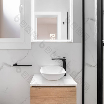 明亮的浴室拥有光滑的极简主义风格特色闪闪发光的白色水槽集惊人的黑色的框架镜子创建现代复杂的