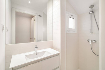 小明亮的浴室淋浴大镜子水槽小窗口自然光清洁白色瓷砖简约设计给空间新鲜的现代感觉