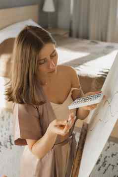 年轻的女人艺术家绘画帆布画架首页卧室艺术创造力概念