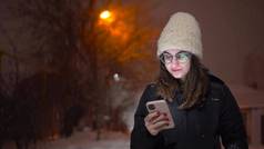 年轻的女人发短信电话雪街女孩眼镜电话手降雪