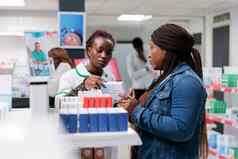 非洲美国药剂师显示客户药物药店架子上