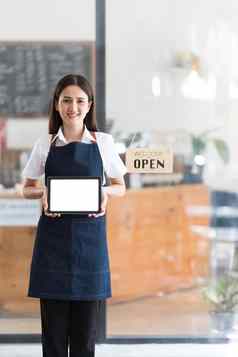 年轻的亚洲业务老板女人围裙开放标志咖啡馆开放显示空白白色屏幕平板电脑
