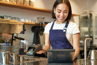 微笑亚洲咖啡师女孩处理订单输入订单回来终端工作计数器咖啡商店