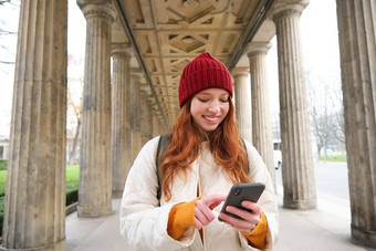 移动<strong>宽带</strong>人微笑红色头发的人女孩背包智能手机街持有移动电话应用程序