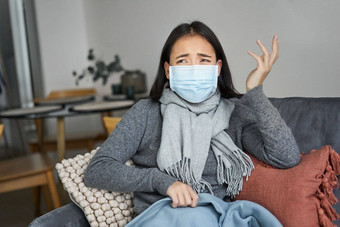 科维德健康概念年轻的亚洲女人医疗脸面具感觉生病的不舒服捕捉流感保护流感坐着生活房间覆盖毯子