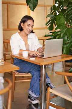 时尚的女商人移动PC坐着咖啡馆工作电脑管理业务喝咖啡