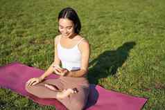 亚洲女孩瑜伽培训应用程序智能手机冥想练习新鲜的空气公园