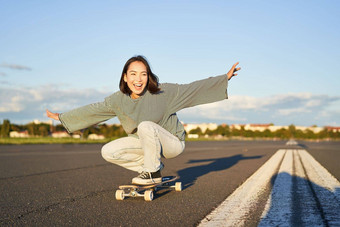 自由幸福快乐亚洲女孩骑冲浪老手空阳光明媚的路笑微笑滑板