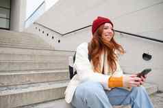 移动手机人年轻的时尚的红色头发的人女孩坐在楼梯电话智能手机应用程序读取smth在线