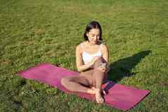 女人公园看瑜伽视频智能手机冥想新鲜的空气坐着橡胶席