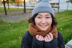 肖像可爱的亚洲女孩他围巾走小镇寒冷的春天天气微笑快乐坐在公园绿色草