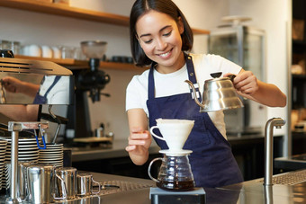可爱的浅黑肤色的女人女孩咖啡师咖啡馆工作人员<strong>倒水水壶</strong>酝酿过滤器咖啡计数器准备订单
