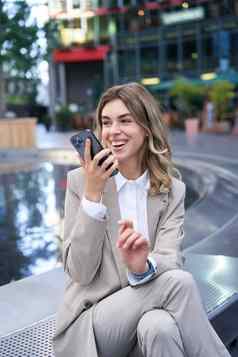微笑业务女人记录的声音消息说话麦克风移动电话坐着喷泉街