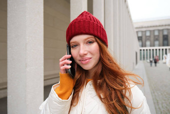 移动宽带人微笑年轻的红色头发的人女人走小镇会谈移动电话调用朋友智能手机互联网使调用在国外