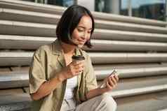 肖像亚洲女人智能手机饮料咖啡手表视频移动电话女孩电话坐在楼梯在户外