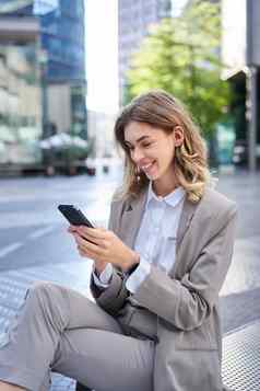 垂直拍摄微笑女商人智能手机应用程序发送消息移动电话或午餐坐着办公室建筑