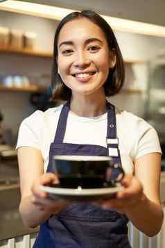 垂直拍摄友好的亚洲女孩微笑服务咖啡咖啡师给杯咖啡准备喝客户端咖啡馆