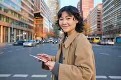 女人走街数字平板电脑持有小工具手站城市中心