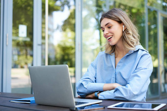 肖像企业女人工作办公室远程坐着移动PC无线耳机参加在线视频会议