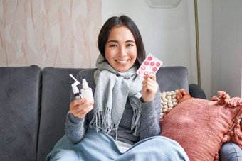 肖像快乐微笑亚洲女孩显示药物治疗痛喉咙喷雾药物流感冷住首页穿温暖的衣服